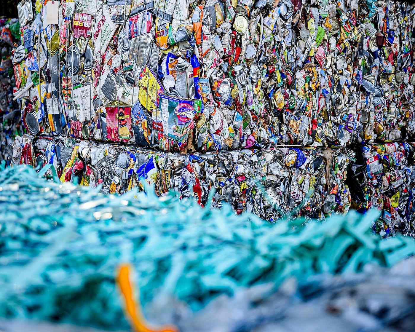 Baled cans and plastic stacked at a materials recovery facility, with sorted plastic in the foreground