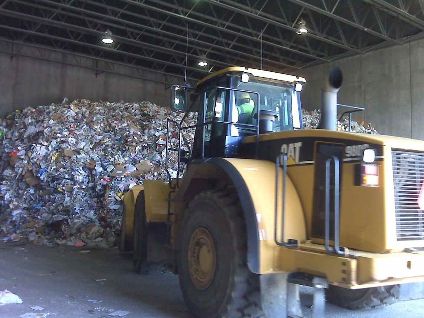 A wheel loader working a pile of mixed waste inside a transfer station